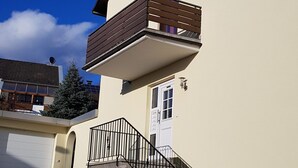 A two-story building with a balcony, a staircase, and a garage. - Gepflegte Dachgeschosswohnung im 2-familienhaus in Ruhiger Wohnlage (Bad Kissingen)