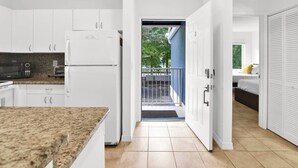 A modern kitchen with white cabinets, a granite countertop, and a built-in microwave. - 350D - Boca Retreat w/ Pool, Parking, Near Evert Tennis & Shops (Boca Raton)