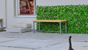 A cat walking on a concrete path in front of a building with a green wall and a wooden bench. - Mpoulakis Apt 46, 3 bedroom family apartment next to my photo studio (Κίσσαμος)