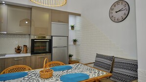 A modern kitchen with a refrigerator, oven, and a clock on the wall. - Mpoulakis Apt 46, 3 bedroom family apartment next to my photo studio (Κίσσαμος)