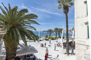 A public square with palm trees, outdoor seating, and a view of the sea. - Deluxe Collection Hotel Kastel (Split)