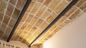 A room with a brick ceiling, a grey sofa with yellow cushions, and a window with sheer curtains. - 1.2 New & stylish flat   Barcelona Touch Apartments (Barcelona)
