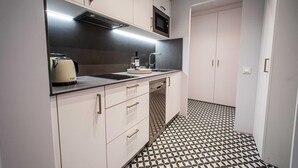 A compact kitchen with white cabinets, a black countertop, a microwave, and a patterned floor. - 1.2 New & stylish flat   Barcelona Touch Apartments (Barcelona)