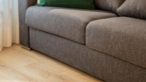 A grey sofa with a green pillow and a patterned pillow.