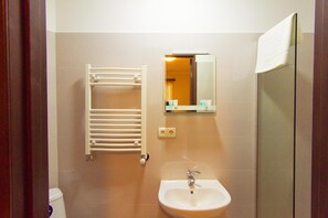 A bathroom with a white sink, a towel rack, a mirror, and a shower. - Hotel Tabi (Tbilisi)