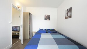 A bedroom with a bed, a television, and a door leading to a bathroom.
