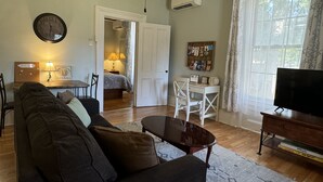 Una sala de estar con sofá, televisor y un comedor con mesa y sillas.