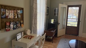 Una habitación con un escritorio de madera, una silla, un televisor y un tablón de anuncios con varios avisos.