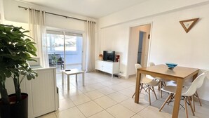 Ein modernes Wohnzimmer mit Essbereich, Fernseher und einer Zimmerpflanze.