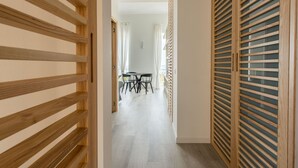 Ein Korridor mit einer Holztäfelungstür, ein Essbereich mit Tisch und Stühlen sowie ein Zimmer mit Holztür und Rollläden.
