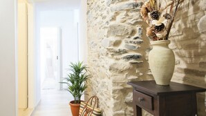 A hallway with a stone wall, a potted plant, a striped bag, a beach ball, and a vase with dried branches. - Casa di Luigi ed Ernestina (Dolcedo)