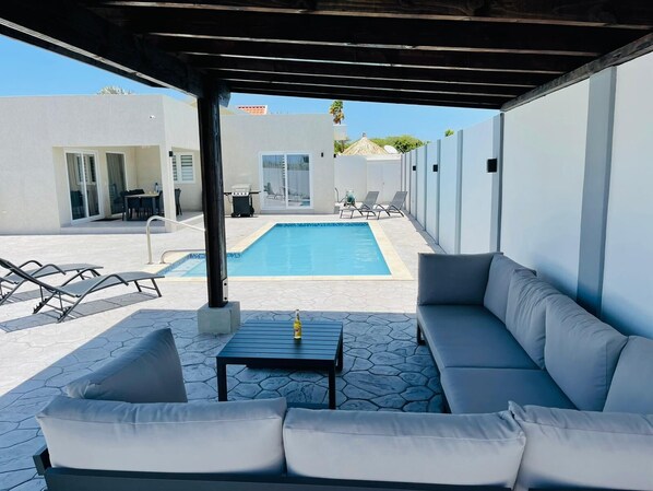 Relax by the pool in a covered patio with a pool table, sofa, and lounge chairs.