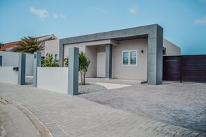 Stylish building with a flat roof and minimalist design, featuring a dark-colored entrance and a landscaped area.