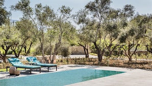 A swimming pool with lounge chairs and a stone wall. - VILLA LAURA (Svoronata, Kefalonia)