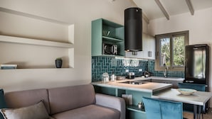 A modern kitchen with teal cabinetry, a black range hood, and a built-in microwave. - VILLA LAURA (Svoronata, Kefalonia)