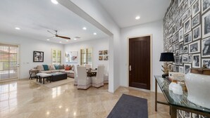 Un salon spacieux avec un plafond haut, un ventilateur de plafond et un coin repas comprenant une table et des chaises.
