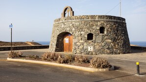 Edifici de pedra amb una porta de fusta, una petita finestra i un penya-bàns.