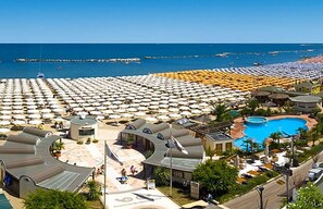 A resort with a large pool, numerous beach umbrellas, and a view of the sea. - Hotel Majorca (Cattolica)