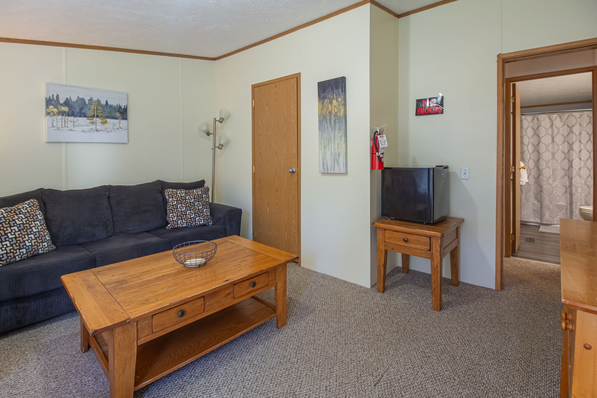 Ein Wohnzimmer mit einer Couch, einem Couchtisch, einem Fernseher und Kunstwerken an den Wänden.