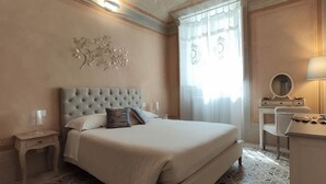 A hotel room with a large bed, a bedside table, a dresser, and a mirror. - Lo Strullo Minisuite (Pisa)