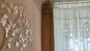 A room with a decorative wall art of leaves, a window with a sheer curtain, and a patterned wall design. - Lo Strullo Minisuite (Pisa)