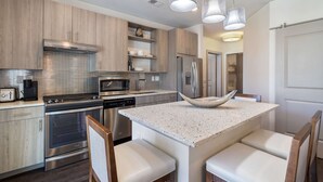 Una cocina moderna con electrodomésticos de acero inoxidable, armarios de madera y una isla central con asientos.