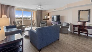 A hotel room with a living area featuring a sofa, armchairs, a TV, and a dining table. - Yacht Club Villas #1-701 Great Location! (North Myrtle Beach)