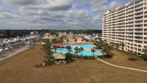 A hotel with a large pool, multiple balconies, and a marina with boats. - Yacht Club Villas #1-701 Great Location! (North Myrtle Beach)