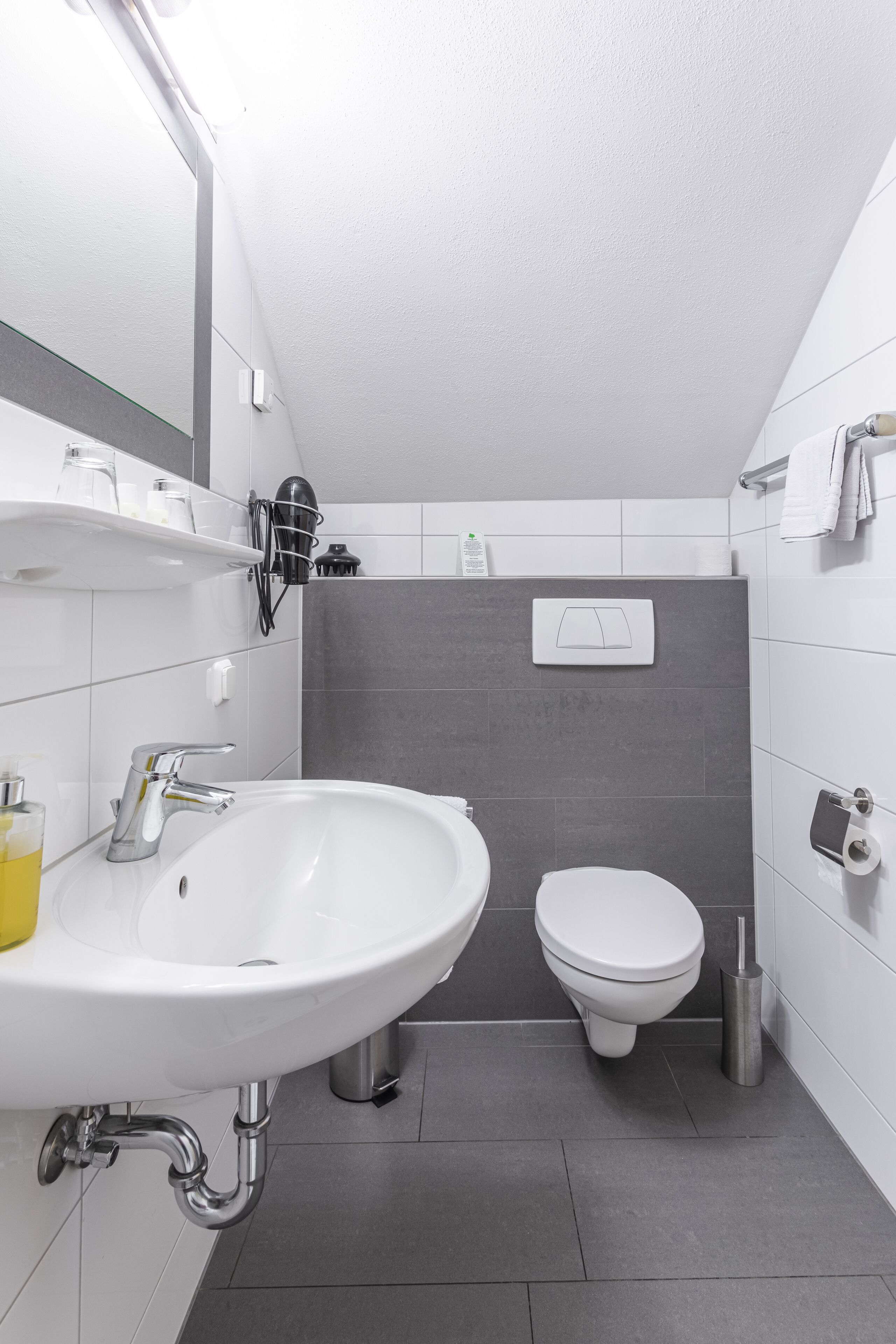 Un baño moderno con un lavamanos blanco, un inodoro y una zona de ducha.