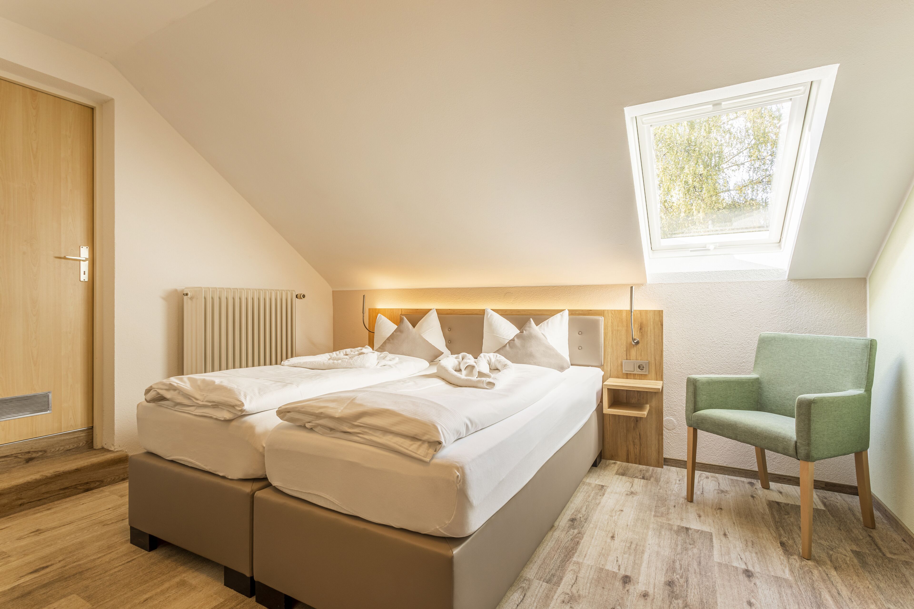 Un dormitorio con una cama grande, una silla, una ventana y un radiador.