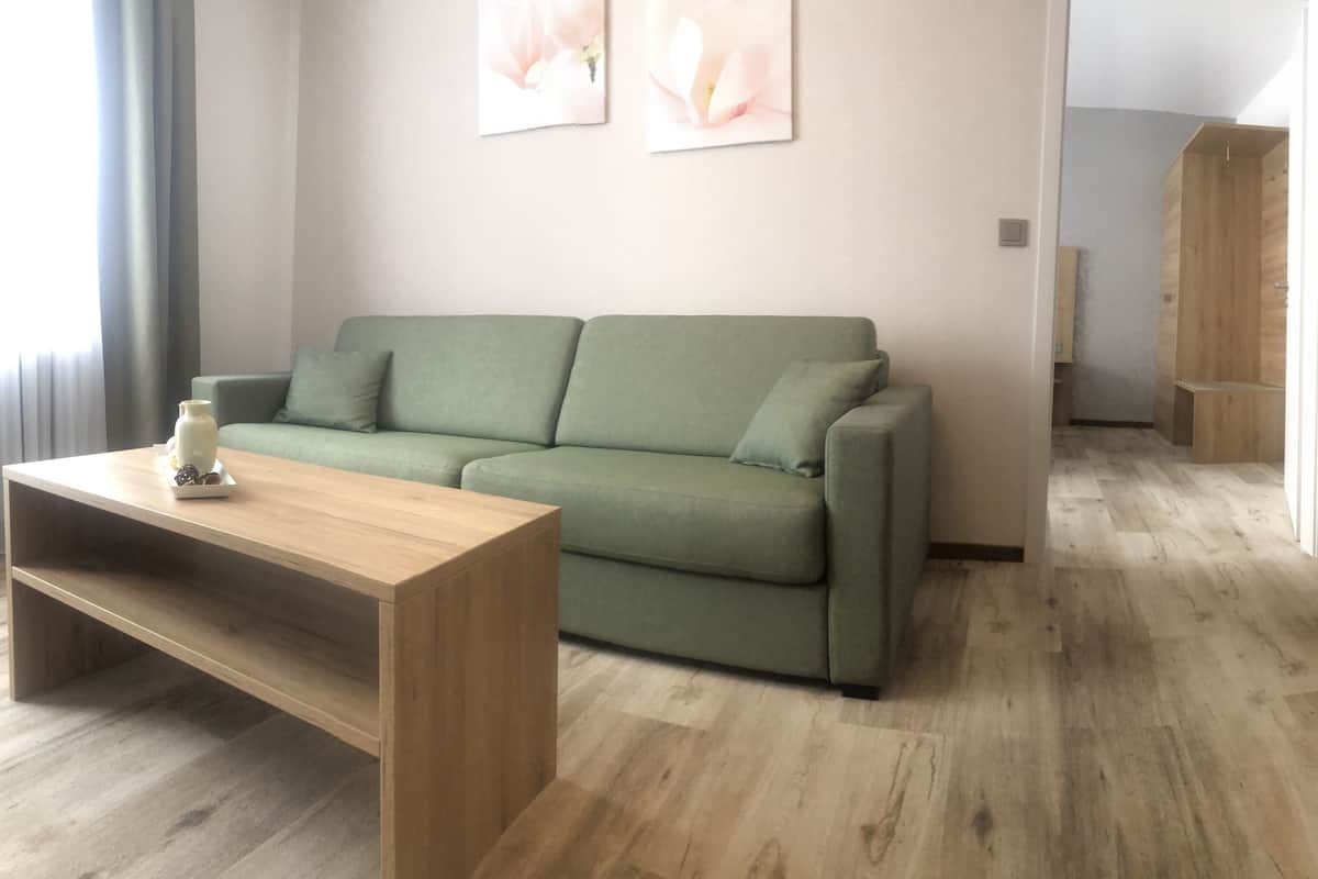 Una sala de estar moderna con un sofá verde, una mesa de centro de madera y un sillón verde.