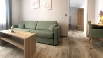 Een moderne woonkamer met een groene bank, een houten salontafel en een groene fauteuil.