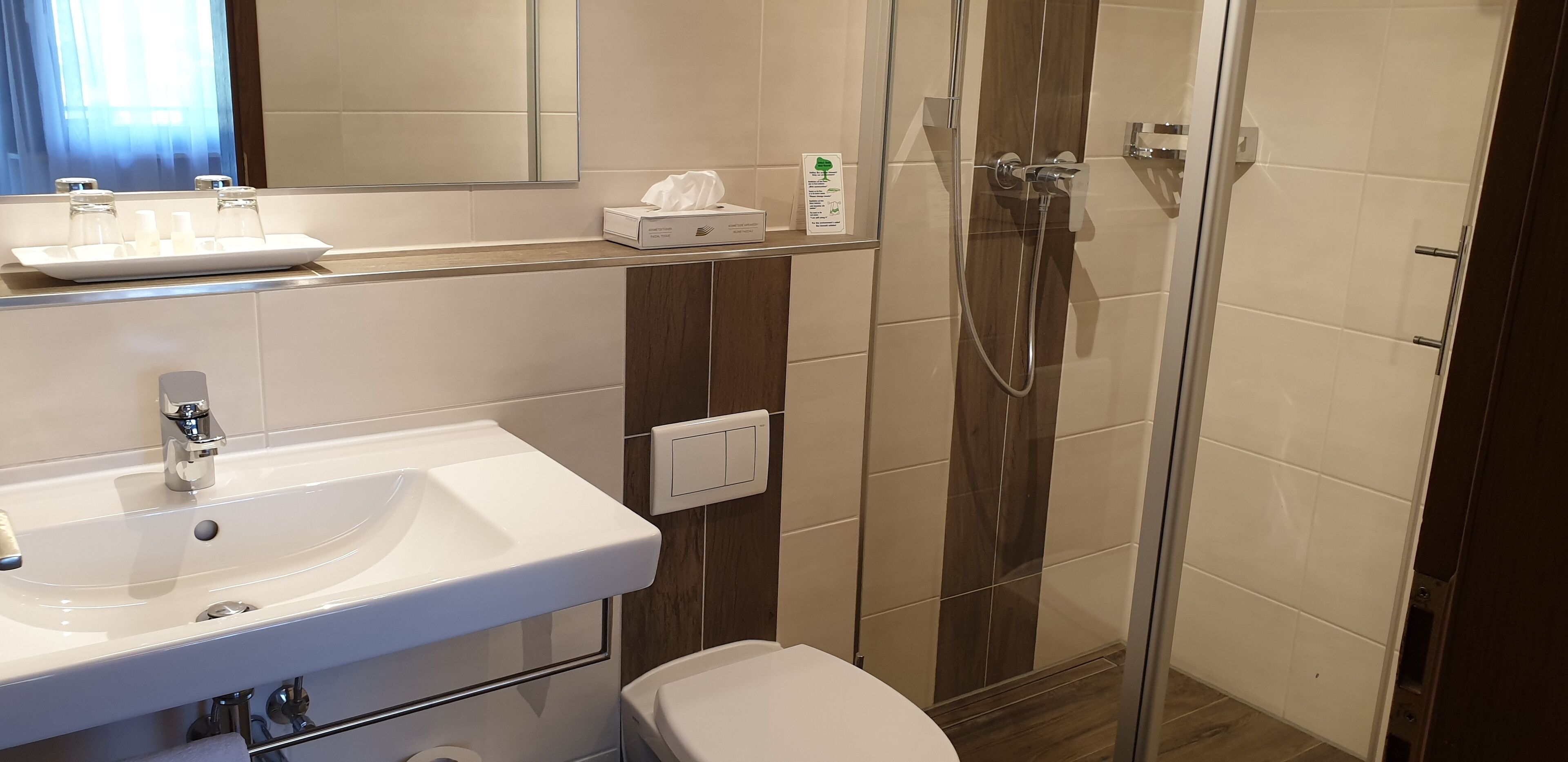A bathroom with a white sink, a mirror, a toilet, and a glass-enclosed shower.
