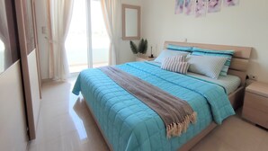 Ein Schlafzimmer mit Bett, Vorhängen, Nachttisch, Spiegel und Wandbildern.