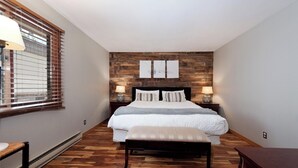 Ein Schlafzimmer mit Holzboden, einem Bett mit weißer Bettdecke, zwei Nachttischlampen und einer Sitzbank.