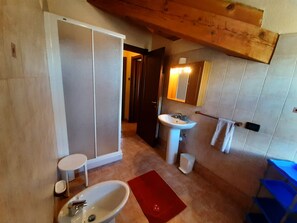Et badeværelse med bruser, vask og toilet.