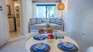 A dining area with a round table set for two, featuring blue and white plates and a bowl of fruit. - Affordable, bright studio with beach access, AC and WiFi! (Akumal)