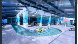 An indoor swimming pool with a diving platform, a water slide, and a lifeguard stand.