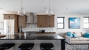 A modern kitchen with a central island, stainless steel appliances, and pendant lighting.