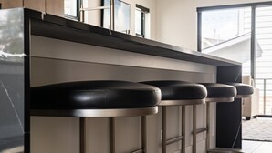 A row of bar stools with a modern design, positioned against a wall with a window and a door.