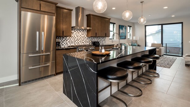 A modern kitchen with a large island, stainless steel appliances, and pendant lighting.