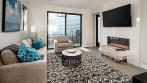 A modern living room with a sofa, armchair, and a fireplace.