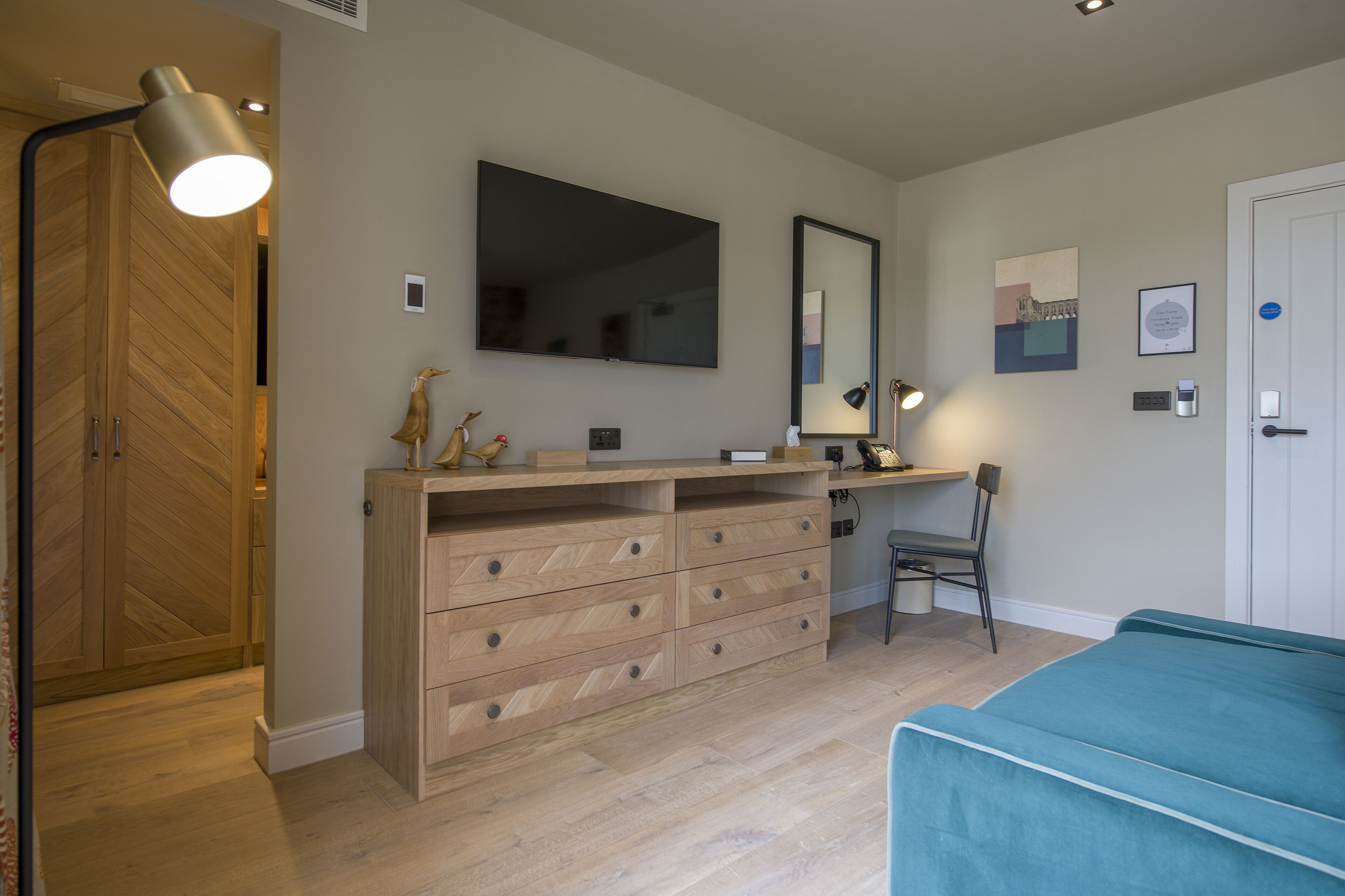 Une chambre moderne avec une armoire en bois, un bureau, une chaise et un lit.