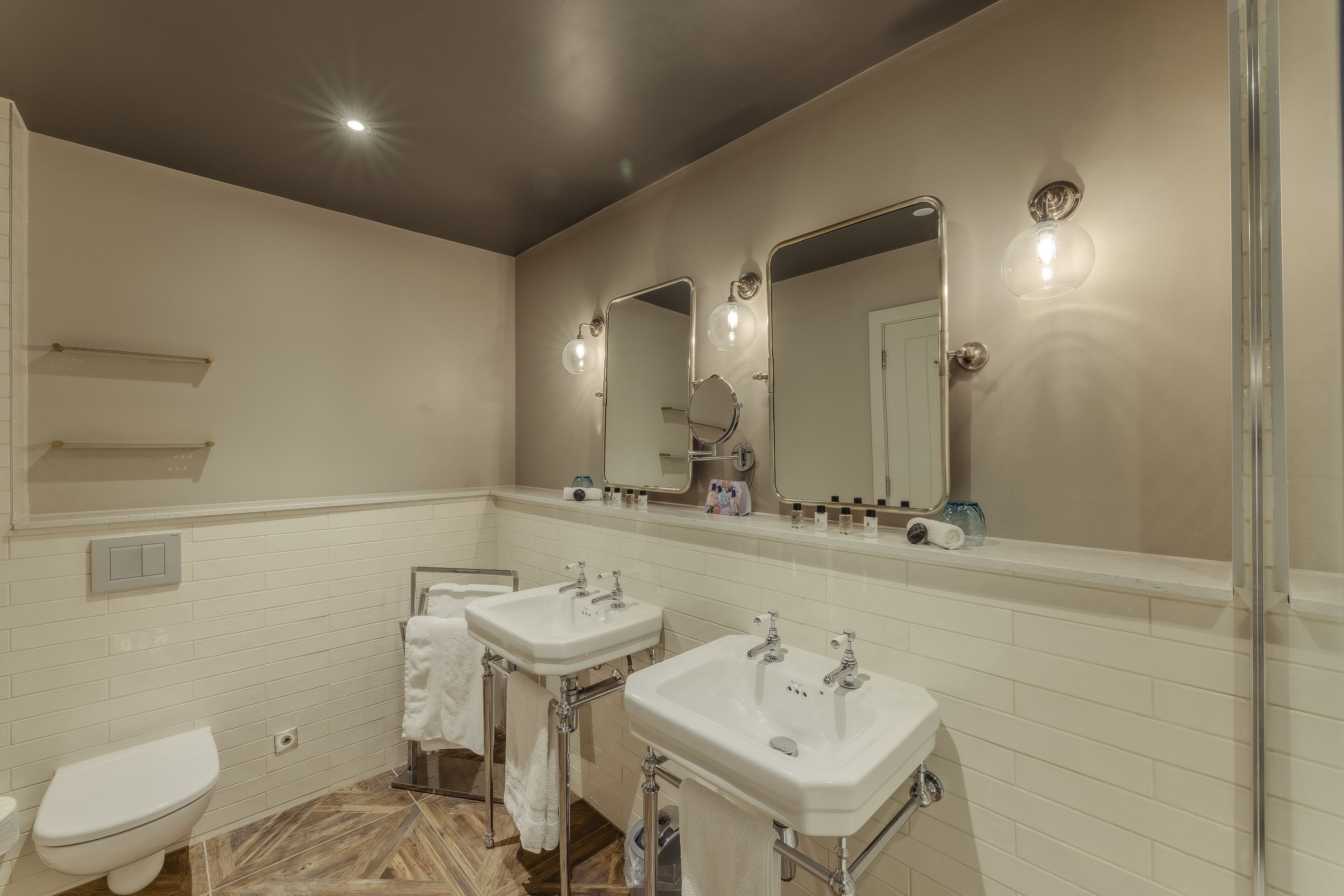 Un baño con dos lavamanos, un inodoro y un espejo grande con luces.