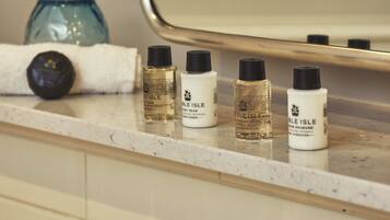 A bathroom counter with toiletries including a bottle of 'Oble Isle' shower gel, a bottle of 'Oble Isle' conditioner, and a bottle of 'Oble Isle' hair spray.