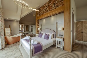 A spacious bedroom with a large bed, a bathtub, and a wooden wardrobe. - Sandburn Hall Hotel (York)