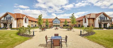 Un hotel con un patio central, asientos al aire libre y una entrada amplia.