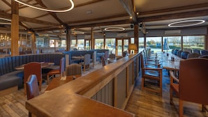 A restaurant with wooden beams, circular ceiling lights, and a mix of booths and tables. - Sandburn Hall Hotel (York)