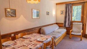 A cozy room with a bed, a dining table set with plates and glasses, and a chair. - 100m from resort center, 7th floor, tv, ski locker, 30m², Les Orres (Les Orres)