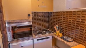 A compact kitchen with a built-in oven, a dishwasher, and a tiled backsplash. - 100m from resort center, 7th floor, tv, ski locker, 30m², Les Orres (Les Orres)